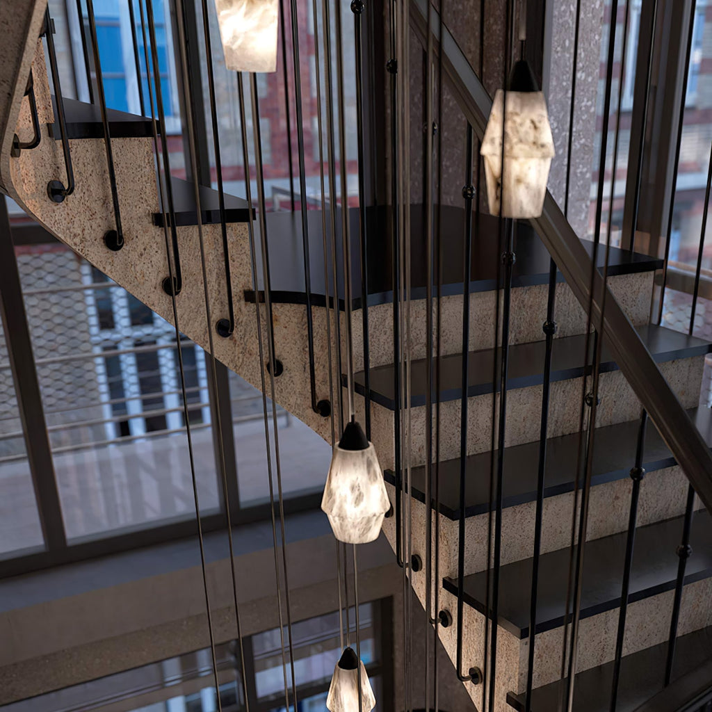 Clérachic Black and White Alabaster Pendant Lights fill a stair void beside speckled stone treads and tall city windows.