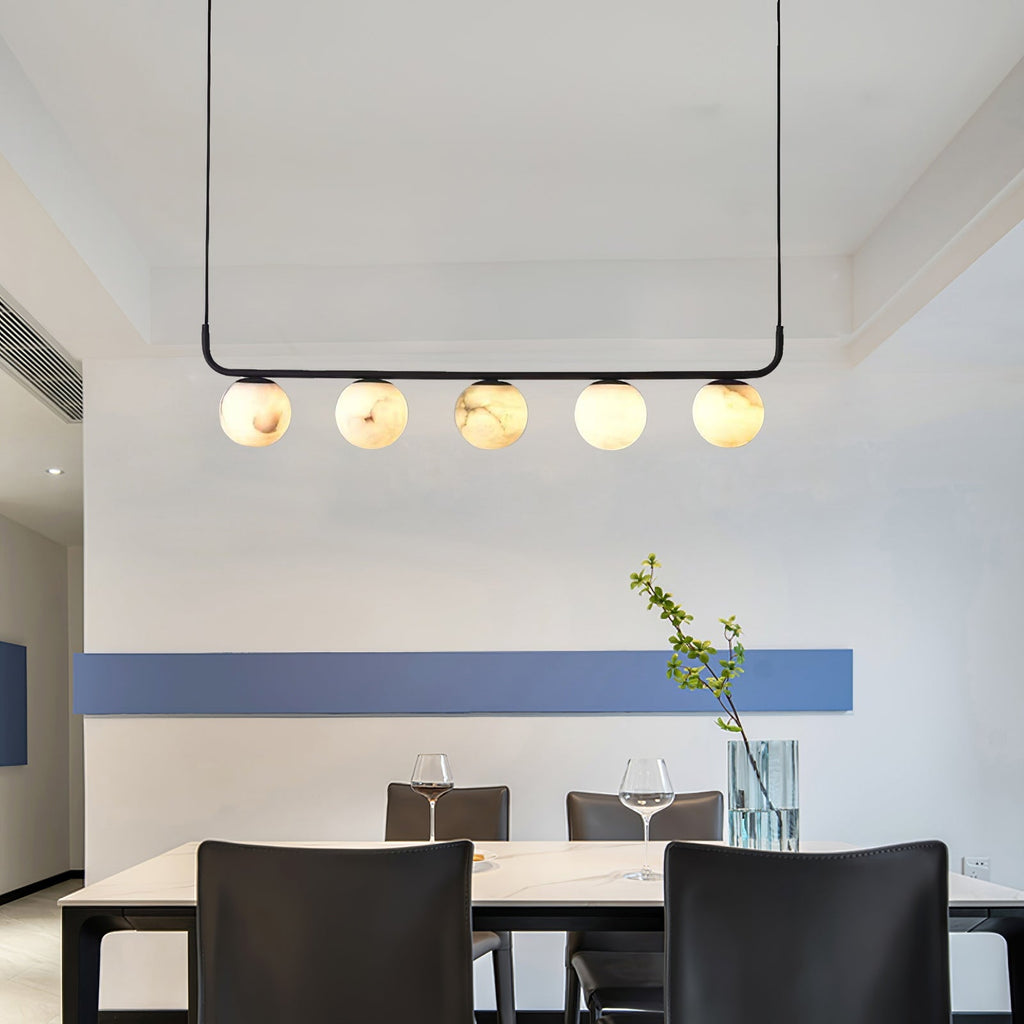 The Clérachic bar pendant hung high in a dining room, five alabaster globes reading warm against a white and blue wall.
