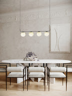 Clérachic four-globe pendant in a classic room with plaster cornice, floating above a white marble oval table.