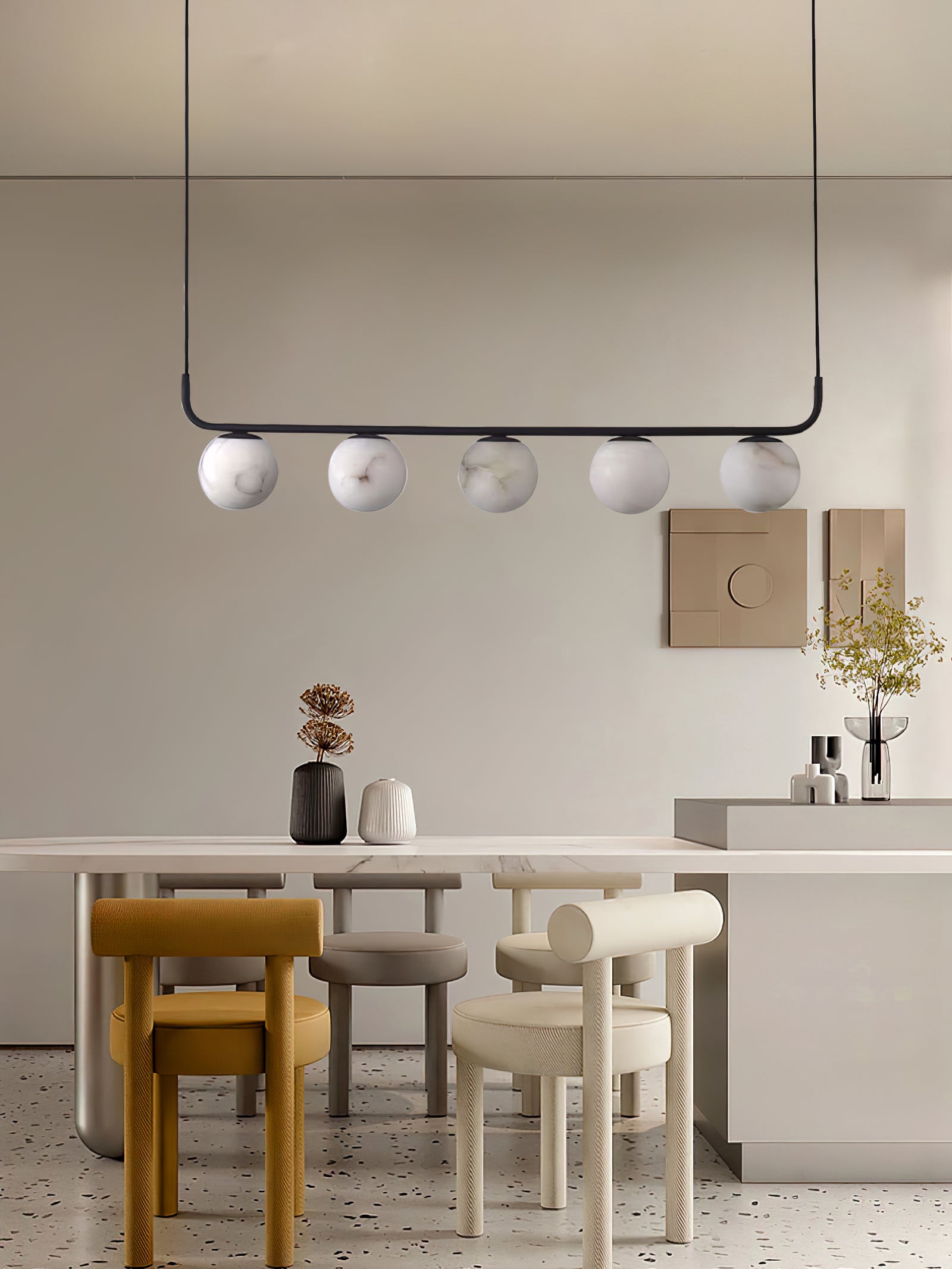 The Clérachic pendant in a beige dining space, five alabaster globes over a stone table and terrazzo floor.