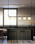 The Clérachic bar pendant above a dark kitchen island, globes catching daylight from the shuttered window behind.