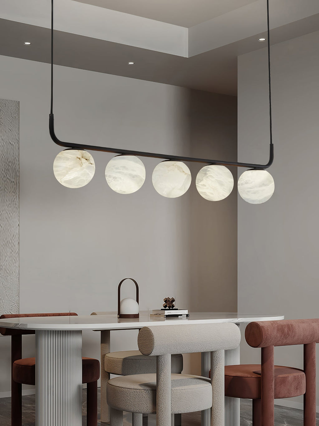 Clérachic pendant over a rounded dining table, five alabaster globes above ribbed pedestals and soft upholstered stools.
