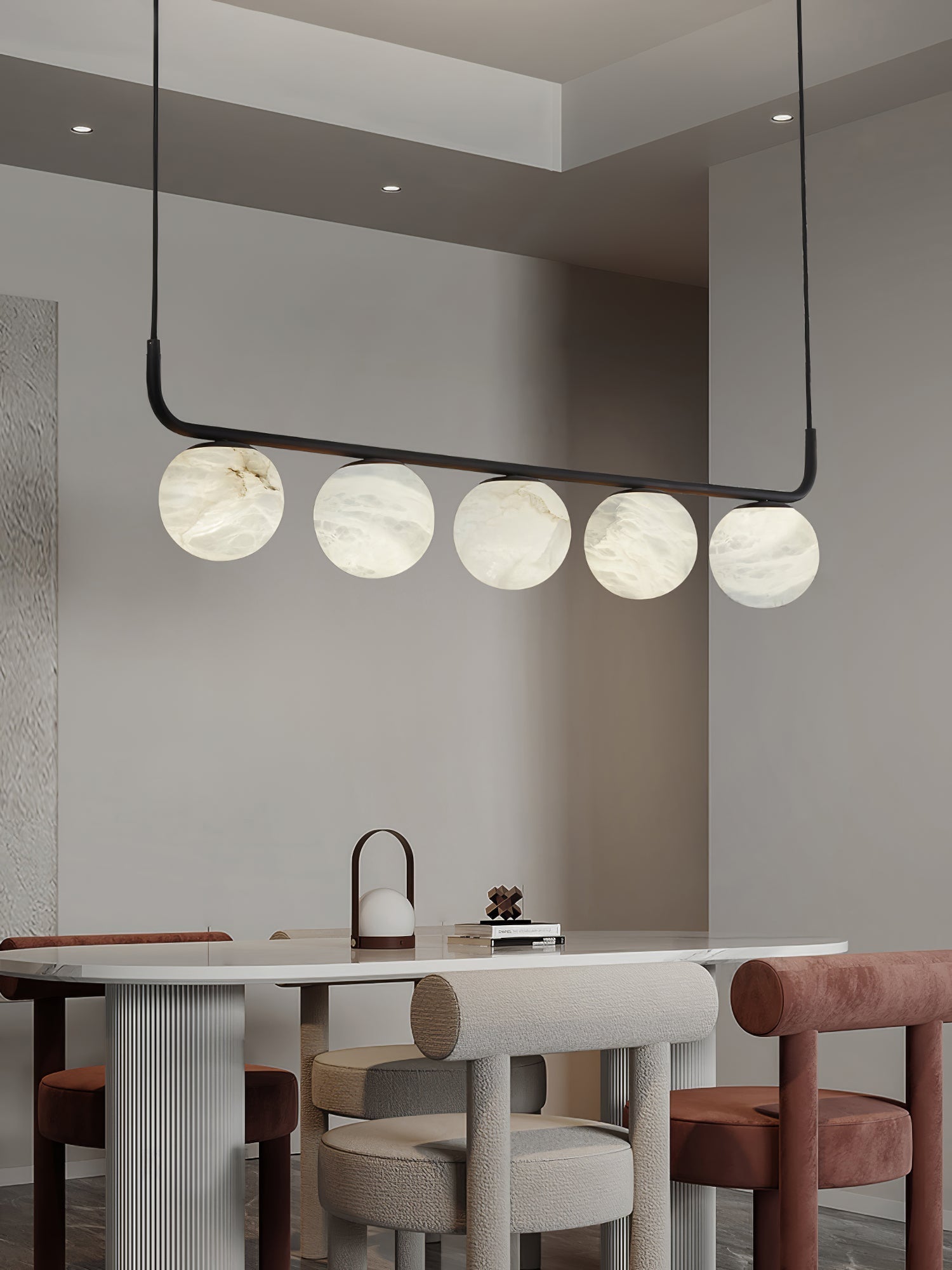 Clérachic pendant over a rounded dining table, five alabaster globes above ribbed pedestals and soft upholstered stools.