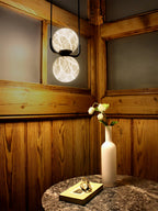 Clérachic two-globe pendant lit in a pine-panelled corner, the stacked spheres reading like two small moons.