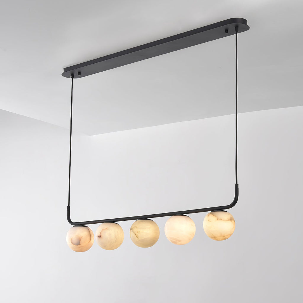 Clérachic bar pendant photographed from below at an angle, five alabaster globes hung beneath the long oval plate.