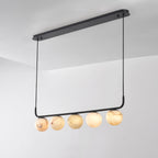 Clérachic bar pendant photographed from below at an angle, five alabaster globes hung beneath the long oval plate.