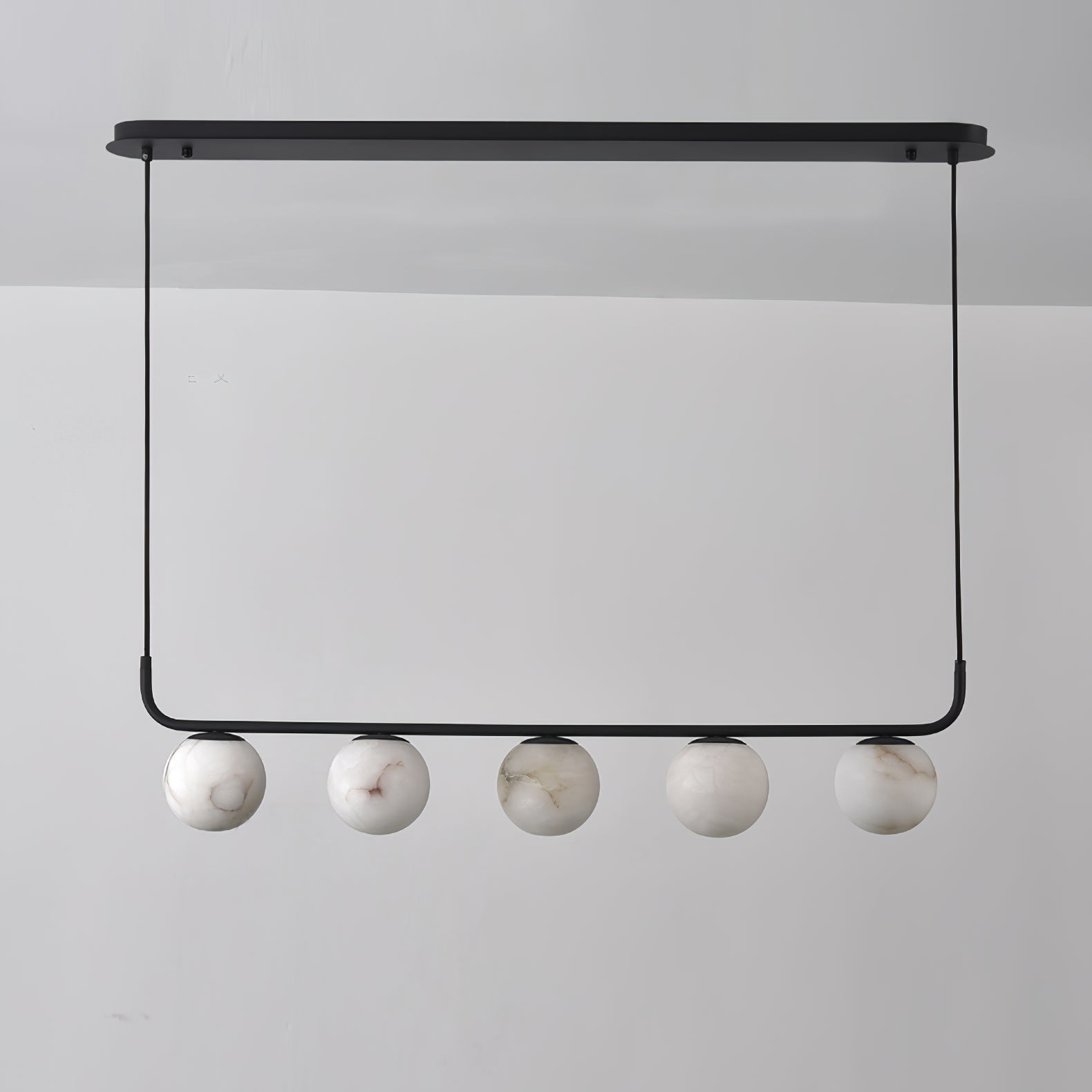 The Clérachic five-globe bar straight on and unlit, cool white stone with soft grey-brown veins against a grey wall.