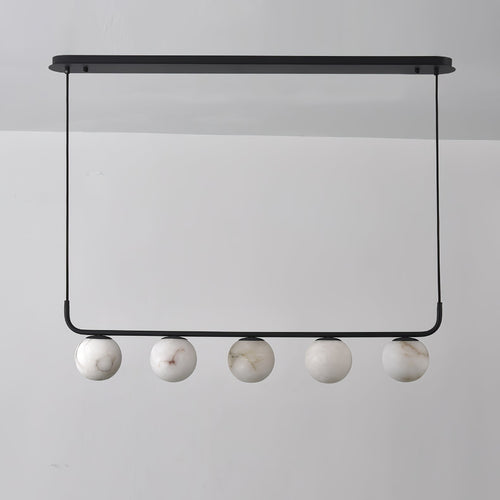 The Clérachic five-globe bar straight on and unlit, cool white stone with soft grey-brown veins against a grey wall.