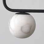 Close detail of one Clérachic alabaster globe seated under the matte-black bar, showing the fitting that holds it.