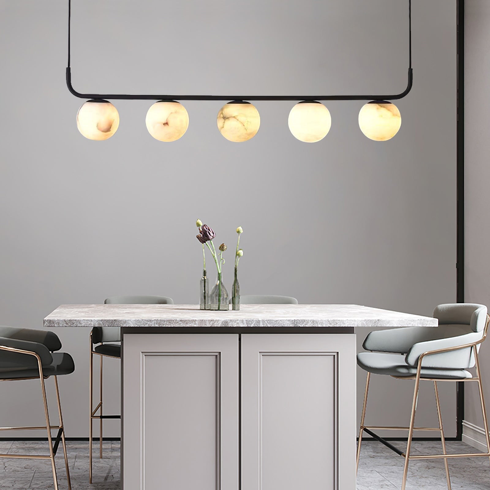 Clérachic five-globe pendant over a marble-topped island, warm globes lit above brass-legged bar stools.