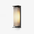 This Clérachic outdoor wall light on a plain white backdrop, with a black frame around a ribbed glass shade glowing warm.