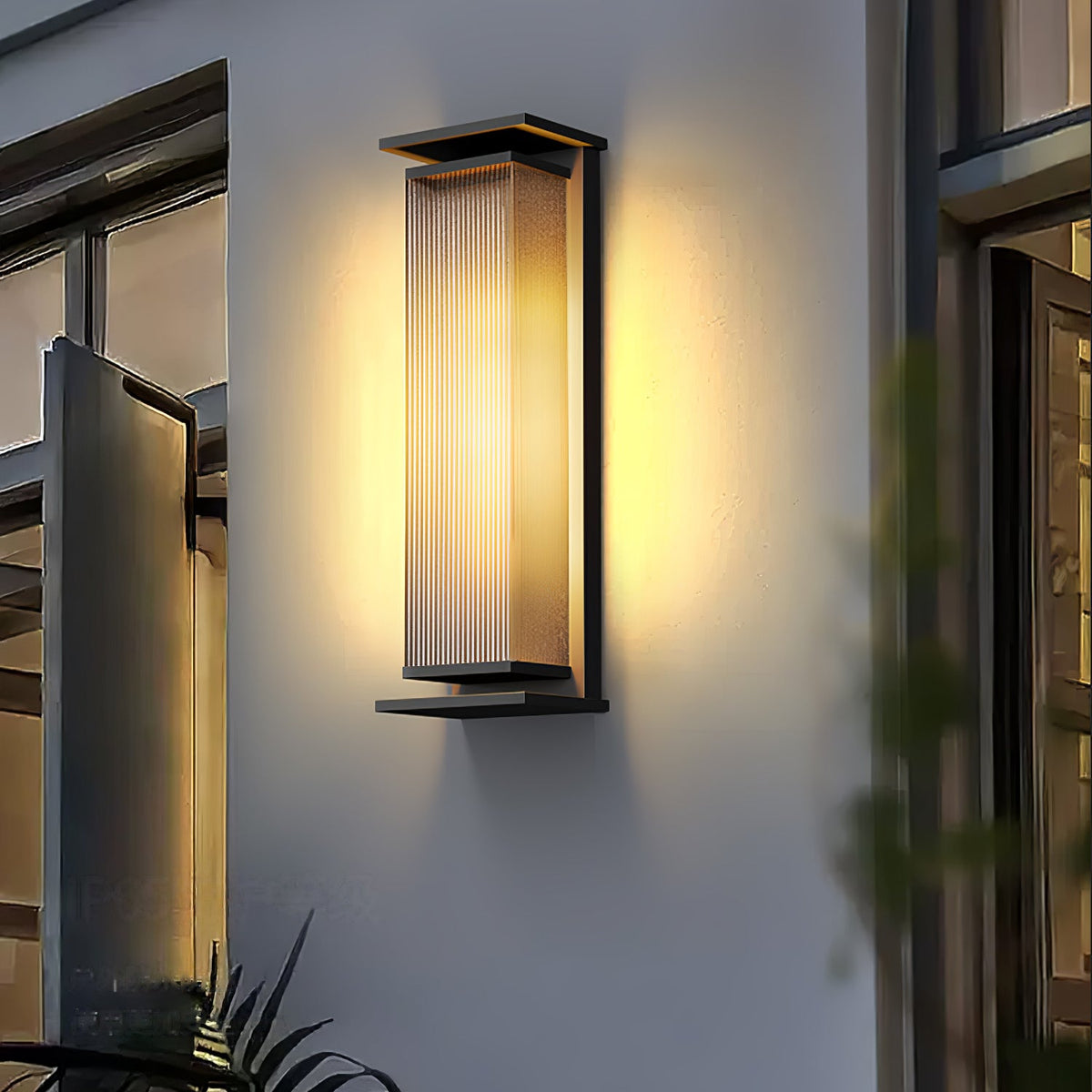 A Clérachic wall light with a ribbed glass shade, lit warm beside a glazed door, with leaves in the foreground.