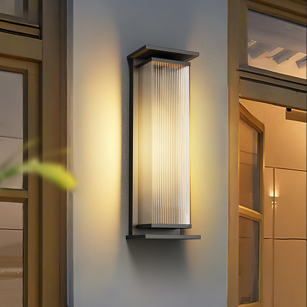 A Clérachic wall light centred between two glazed doors, its ribbed shade glowing warm in a black frame.