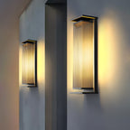 Two Clérachic wall lights at different heights, angled to show the black frame and glowing ribbed shades, on a grey wall.