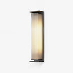 This Clérachic wall light in a tall size on a pale backdrop, lit warm behind its ribbed glass shade.