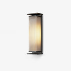 A mid-height Clérachic wall light with a black frame and glowing ribbed shade, on a pale backdrop.