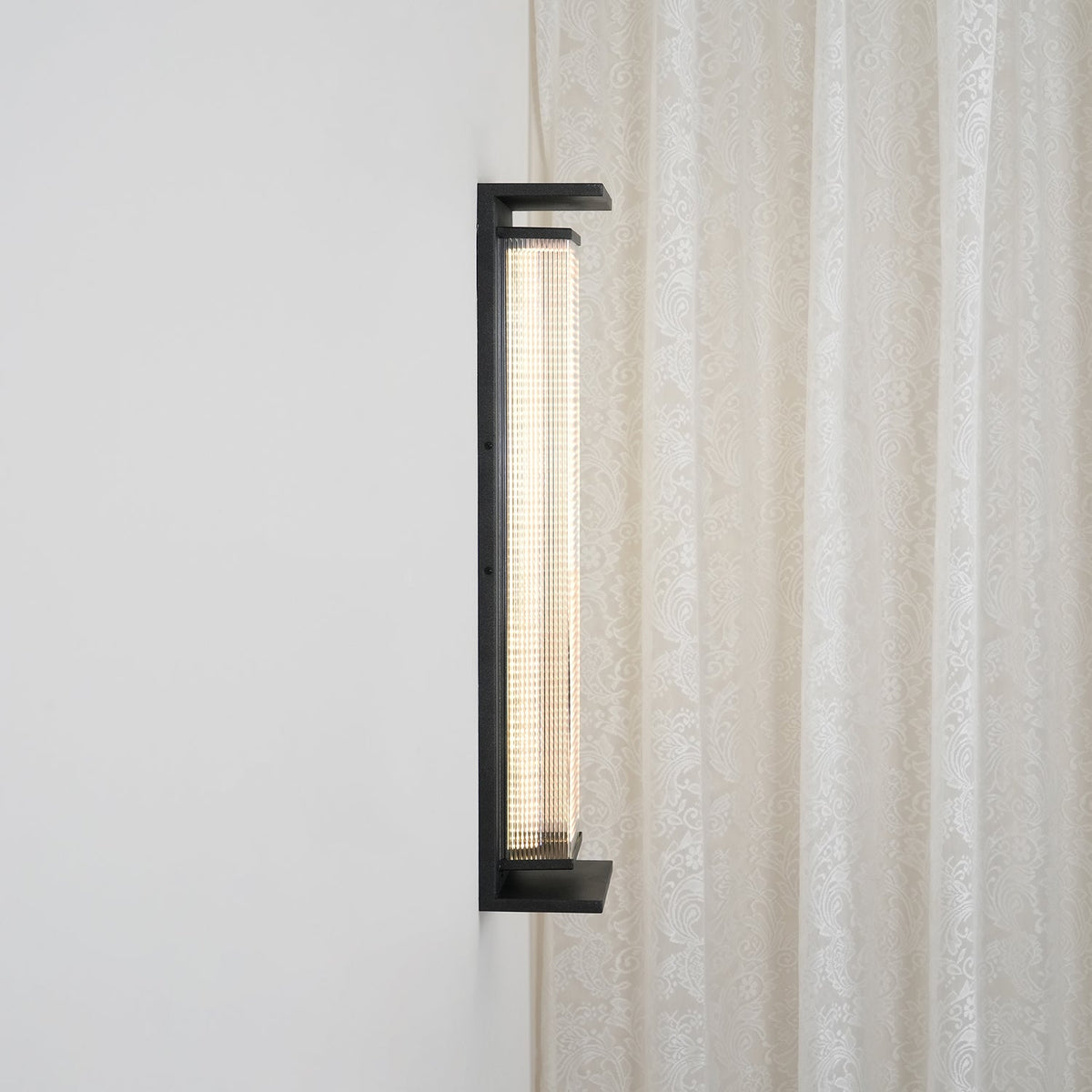 Side view of this Clérachic wall light, showing how far the black frame and ribbed shade stand out from the wall.