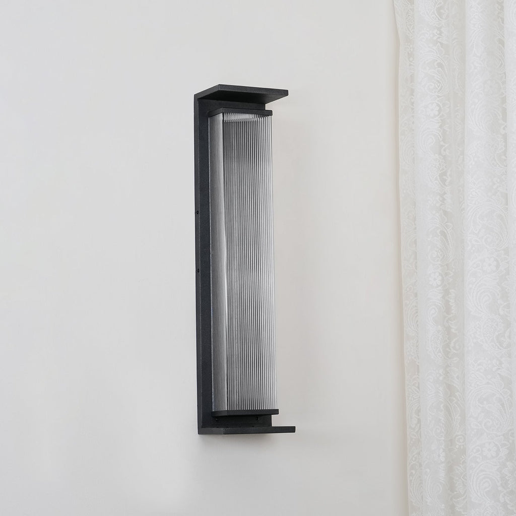 A Clérachic wall light unlit, angled slightly to show the black shelf at its base and the fine ribs in the glass.