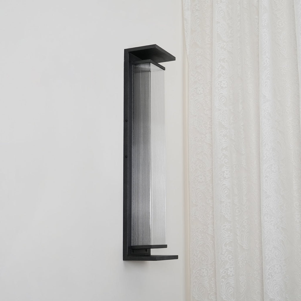 Side view of this Clérachic wall light, unlit, with clear ribbed glass and a black base shelf.