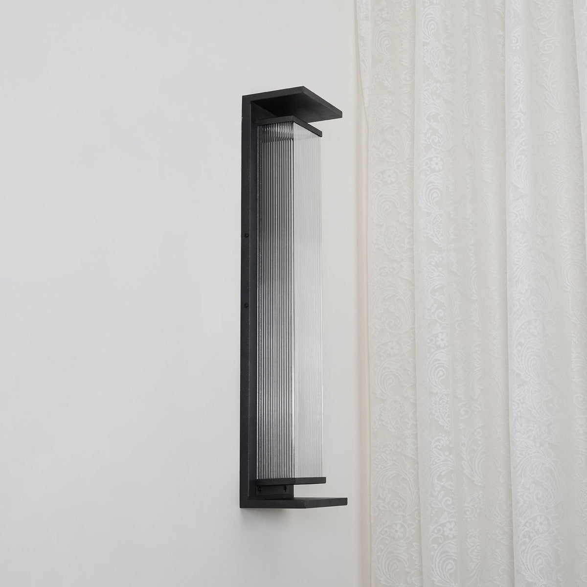 Side view of this Clérachic wall light, unlit, with clear ribbed glass and a black base shelf.