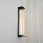 Front view of this Clérachic wall light lit warm white, with a pale strip of light behind the fluted glass in a black frame.