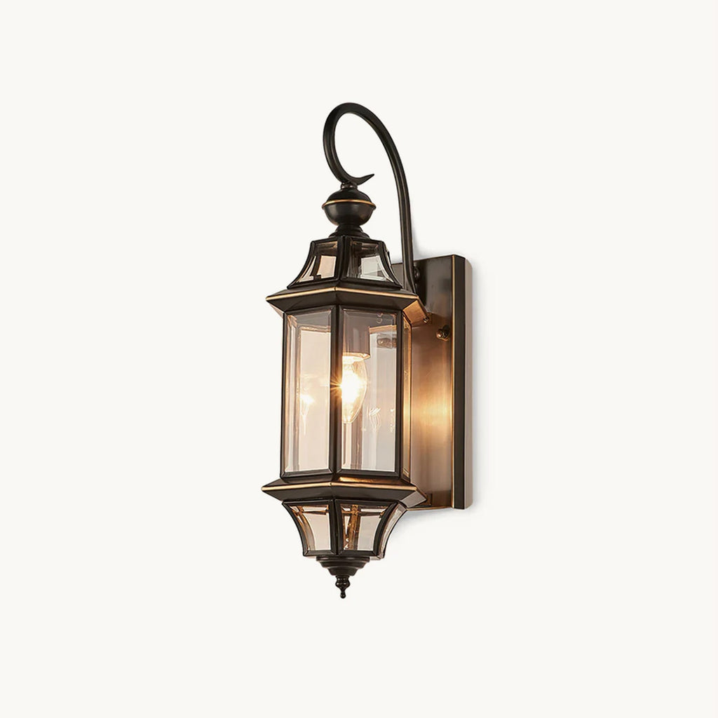 A Clérachic outdoor wall lantern with a black curved arm, clear glass panels and a small pointed finial, on a plain white backdrop.