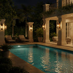 Several Clérachic wall lanterns light the columns of a terrace at night, beside a pool and sun loungers.