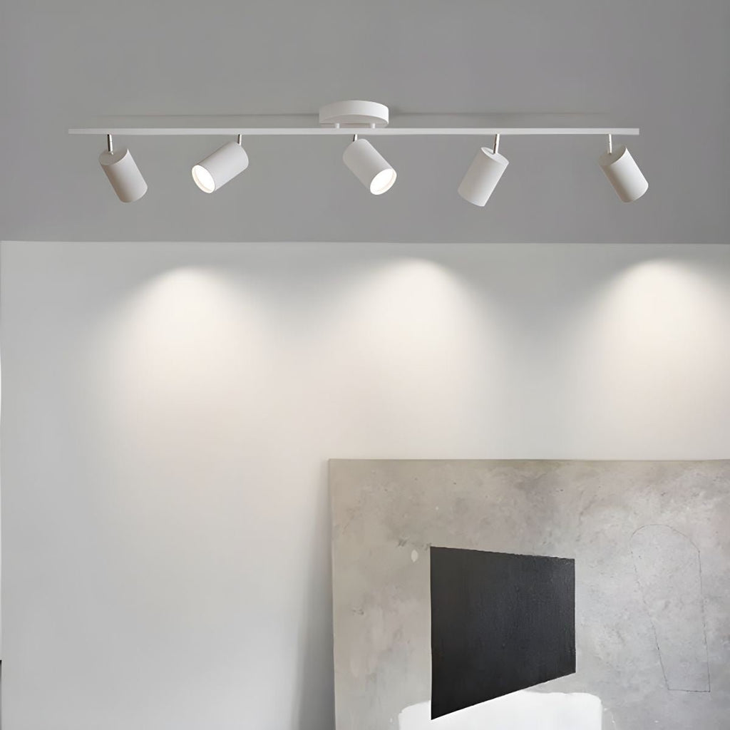 A white Clérachic five-head track light on a grey ceiling casts scalloped pools of light over a large abstract canvas.