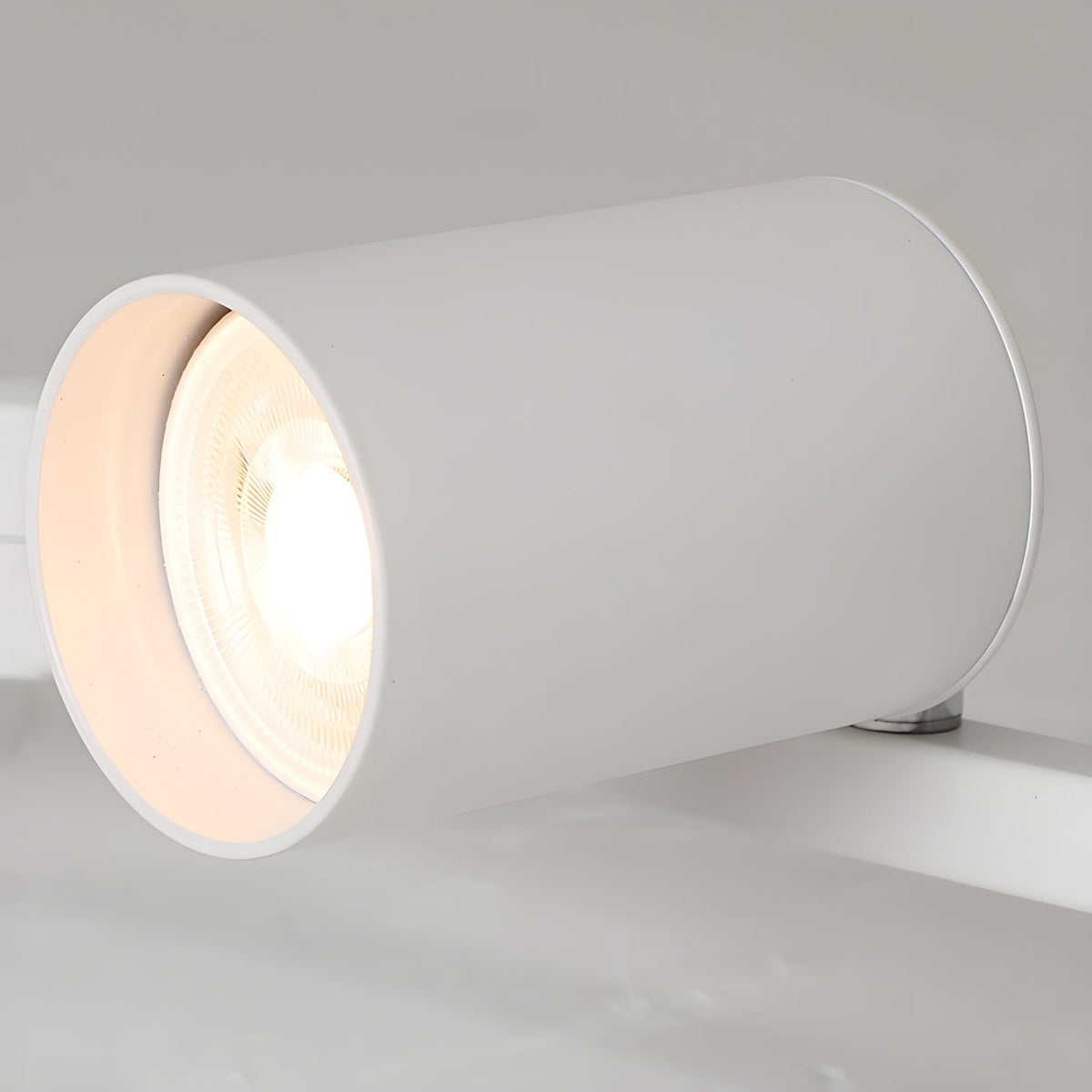 Close view of one white Clérachic spotlight head, showing the lit bulb recessed inside its cylinder.