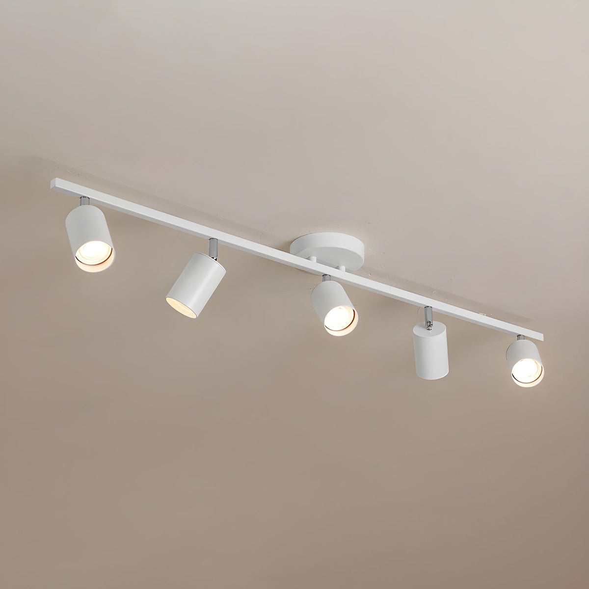 A white Clérachic five-head track light on a warm beige ceiling, with the heads pointing in different directions.