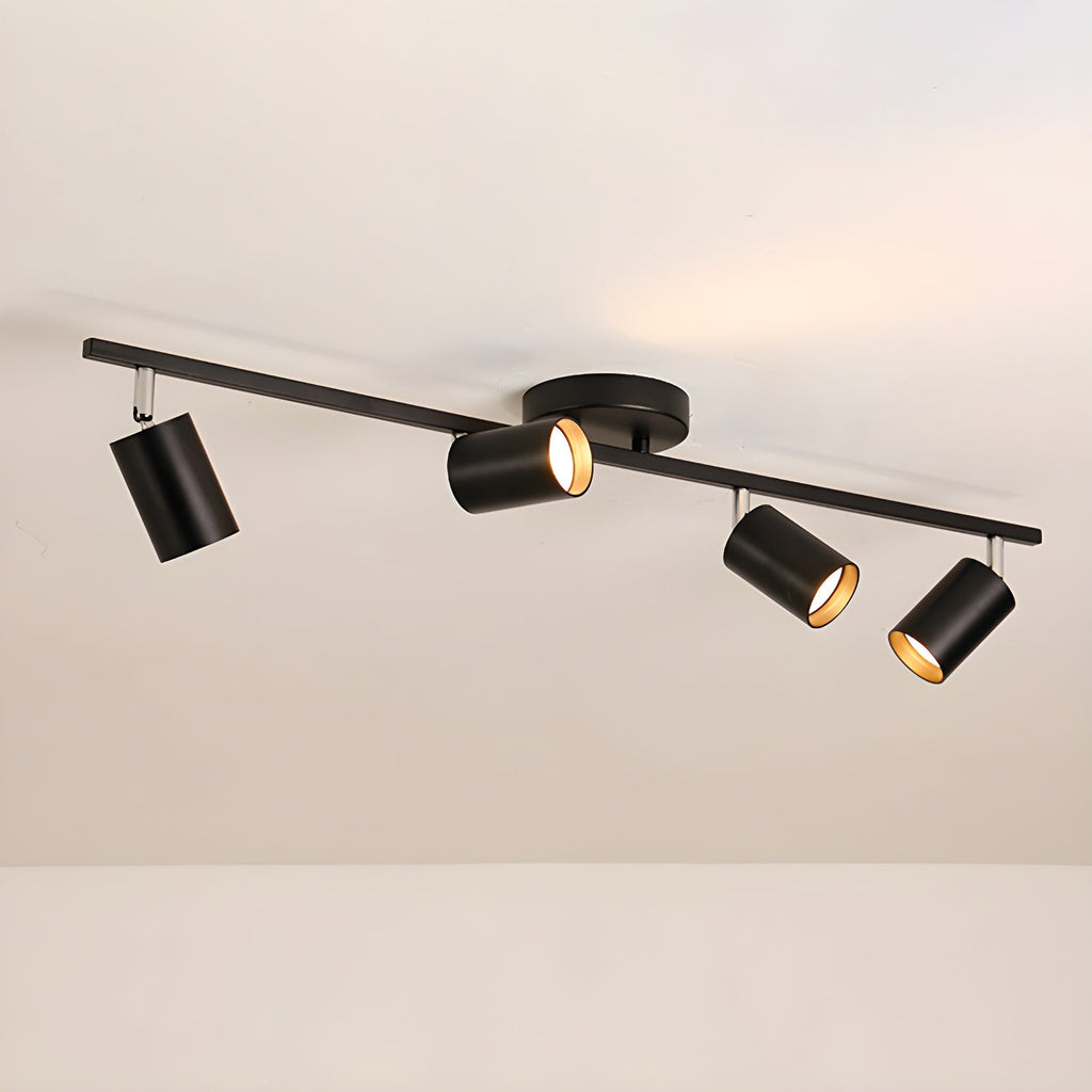 A black Clérachic four-head track light on a beige ceiling, with a round canopy and gold-lined heads.