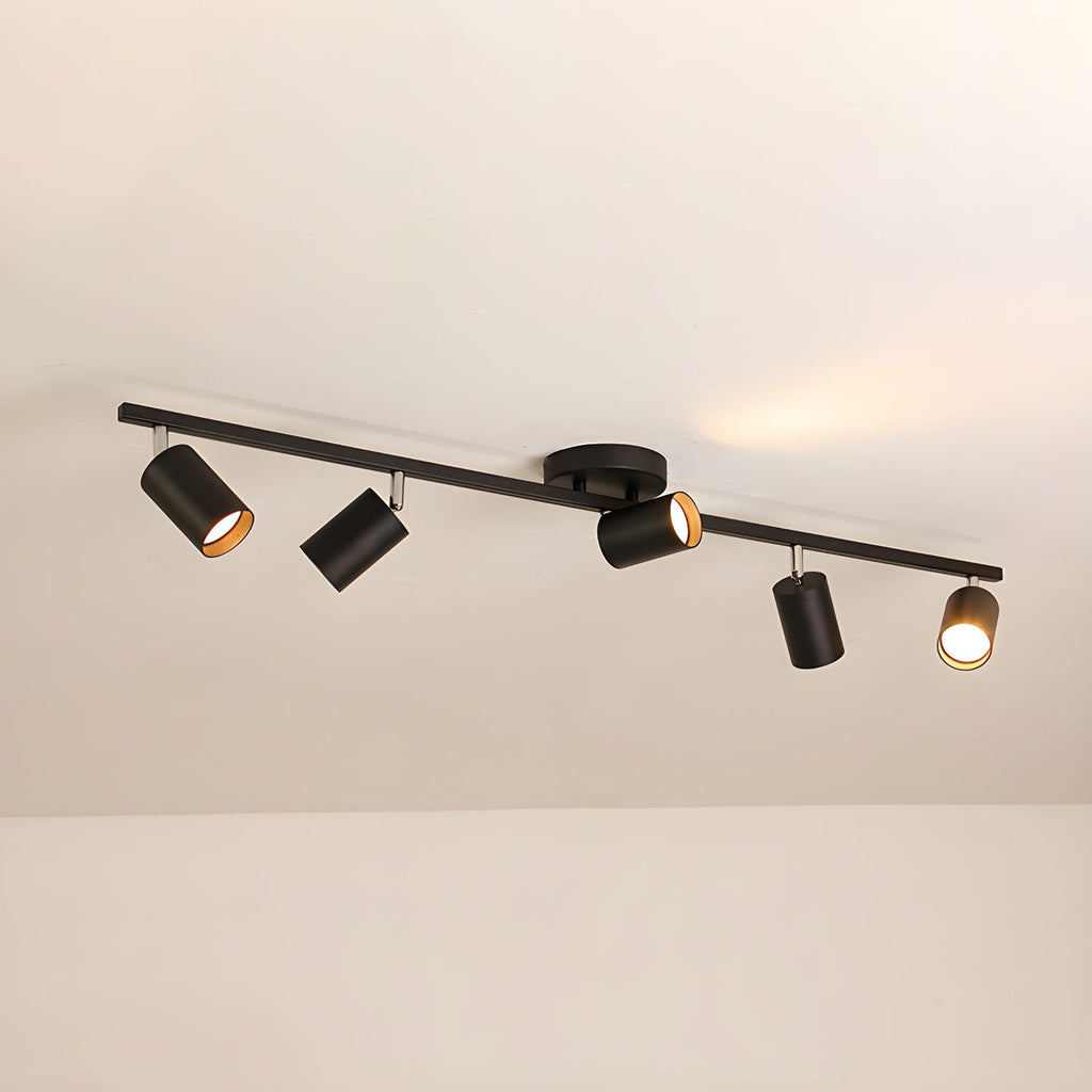 A black Clérachic five-head track light along a beige ceiling, its gold-lined heads angled in different directions.