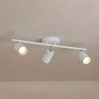 A white Clérachic three-head track light with a round canopy on a pale ceiling, two of its bulbs glowing.