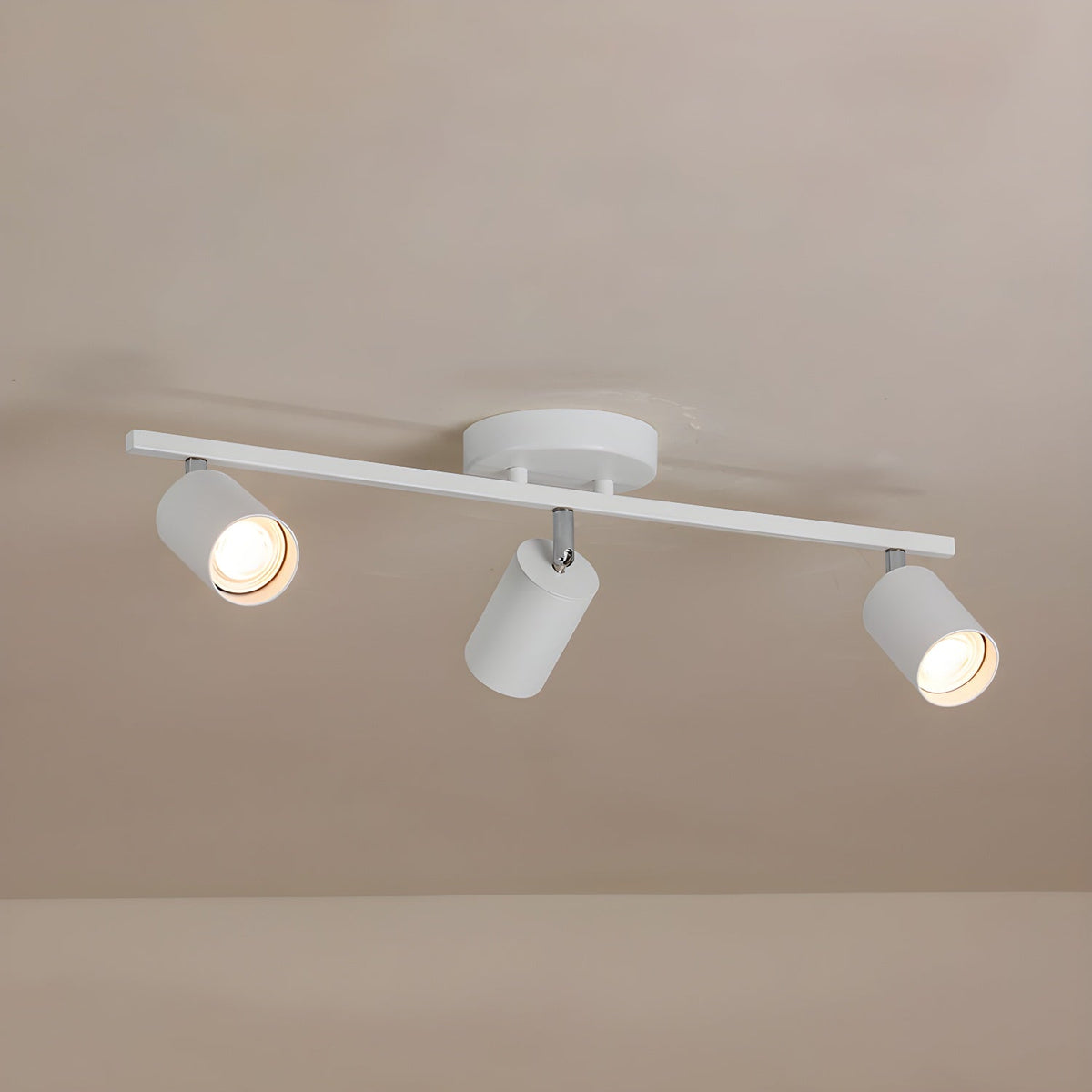 A white Clérachic three-head track light with a round canopy on a pale ceiling, two of its bulbs glowing.