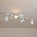 A white Clérachic four-head track light on a pale ceiling, with a warm glow cast by the lit heads.