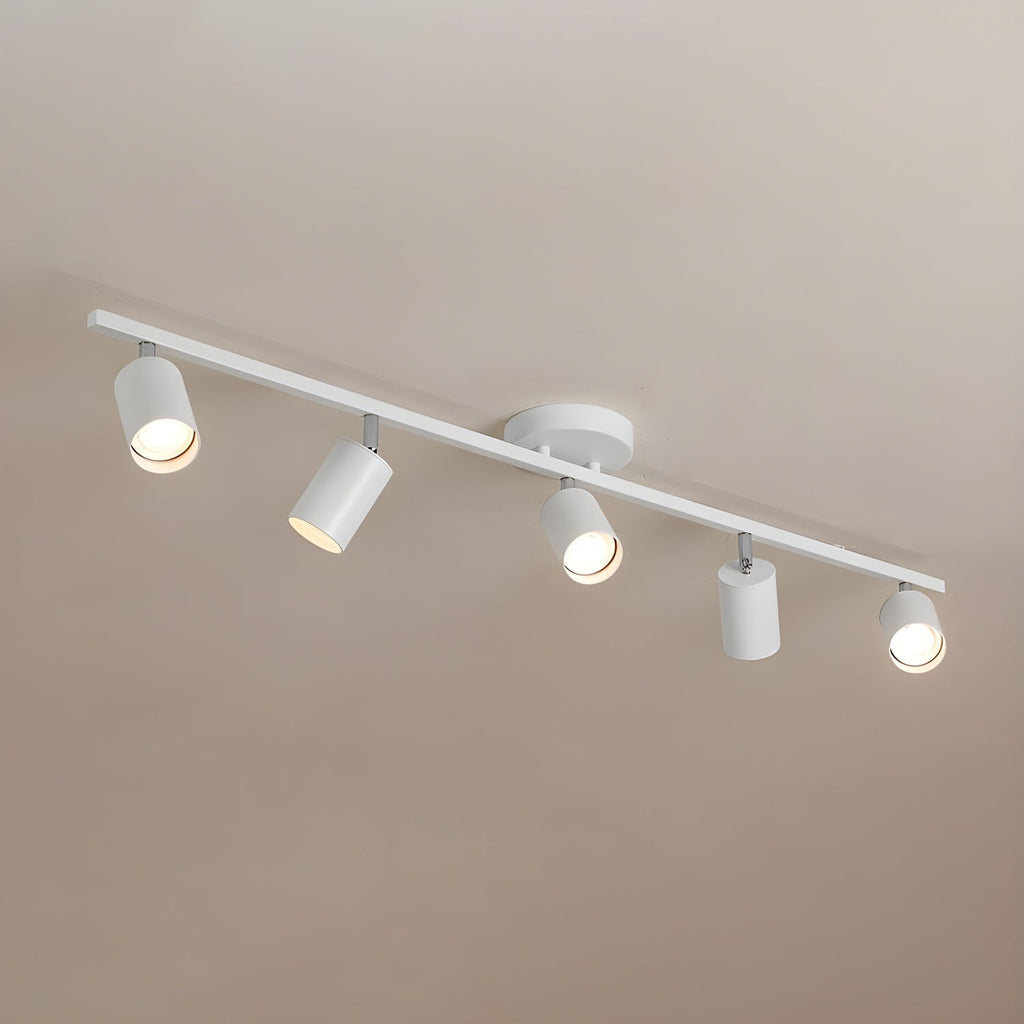 A white Clérachic five-head track light on a warm taupe ceiling, with its heads angled and bulbs lit.