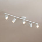 A white Clérachic five-head track light on a warm taupe ceiling, with its heads angled and bulbs lit.