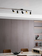 Clérachic five-head track light in black on a ceiling above grey wall panels and a marble table with a dark bowl.