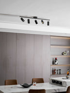 A black Clérachic track light with five heads, seen from a lower angle against grey panelling and a bottle shelf.