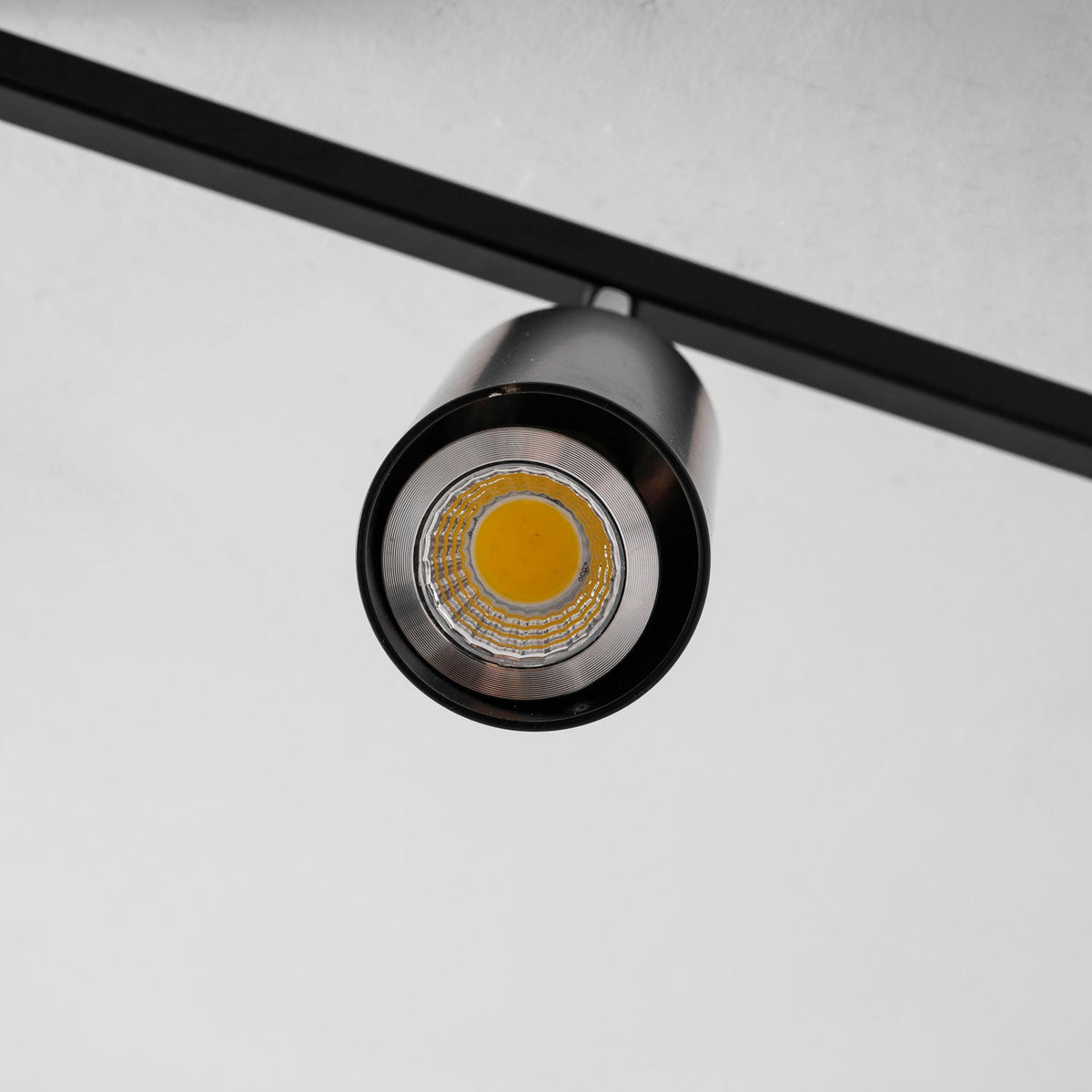 Close view of a black Clérachic spotlight head, with its warm bulb set in a silver reflector ring.