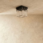Clérachic ceiling light switched off: four rectangular textured glass panels beneath a square black metal mount on pale plaster.