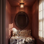 Clérachic compact glass ceiling light glowing above an oval mirror and a marble basin in a narrow wine-red alcove.