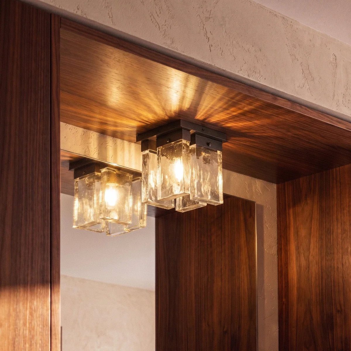 Clérachic bubbled glass ceiling light with a black mount, lit warm and mirrored beside walnut panelling and plaster.