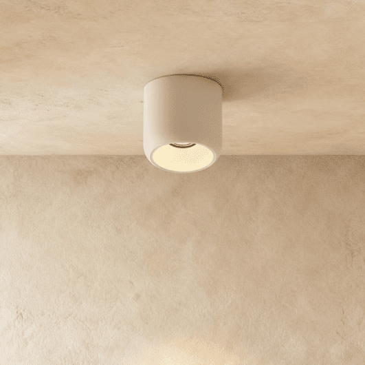 Clérachic downlight in white, a compact cylinder surface-mounted on the ceiling and casting a soft warm pool of light.