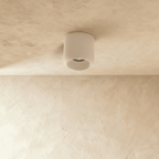 Clérachic downlight in white, the round cylinder housing catching light against a textured plaster ceiling.