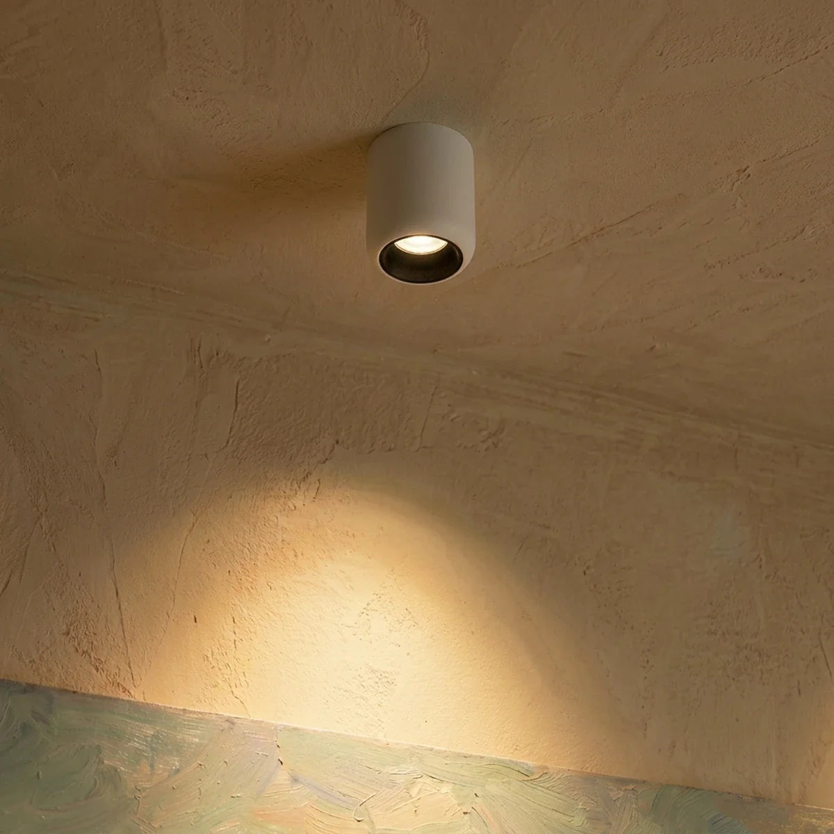 Clérachic downlight in white mounted at an angle, its beam falling softly across a plaster wall corner.