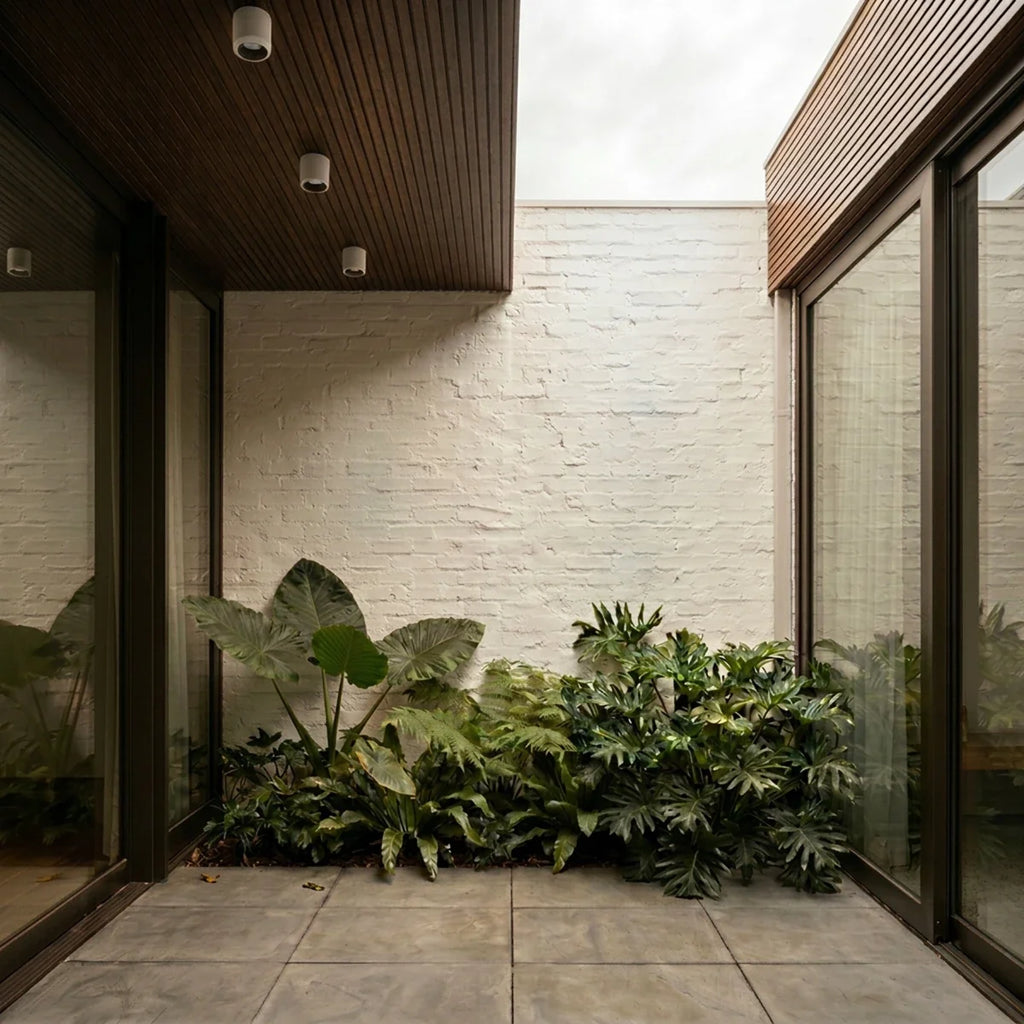 Clérachic downlights in white recessed into a wood-slat covered ceiling, lighting a courtyard with tropical plants.