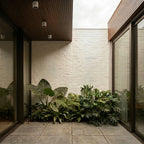 Clérachic downlights in white recessed into a wood-slat covered ceiling, lighting a courtyard with tropical plants.