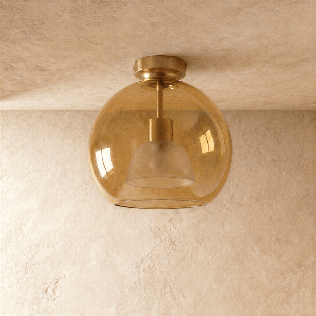 Clérachic wide amber glass globe ceiling light glows warm, its inner dome shade visible through the glass.