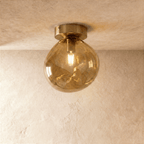 Clérachic amber hand-blown glass globe with a dimpled, organic texture flush-mounts on a warm plaster ceiling.
